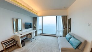 Una habitación de hotel con un ventanal grande, un escritorio con una silla, un sofá y un televisor.