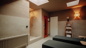 Un cuarto de spa con un radiador, un estante de madera con toallas, y una lámpara fijada a la pared.