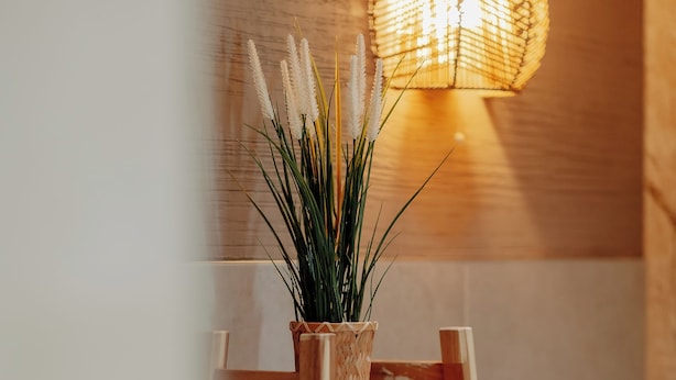 Una escalera de madera con una cesta tejida que contiene una planta, y estantes con toallas dobladas cuidadosamente.