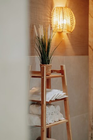 A wooden ladder with a woven basket holding a plant, and shelves with neatly folded towels. - Parkhotel Papenburg by Hackmann (Papenburg)