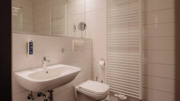 Une salle de bain moderne avec un lavabo, des toilettes et un miroir, le tout de couleur blanche.