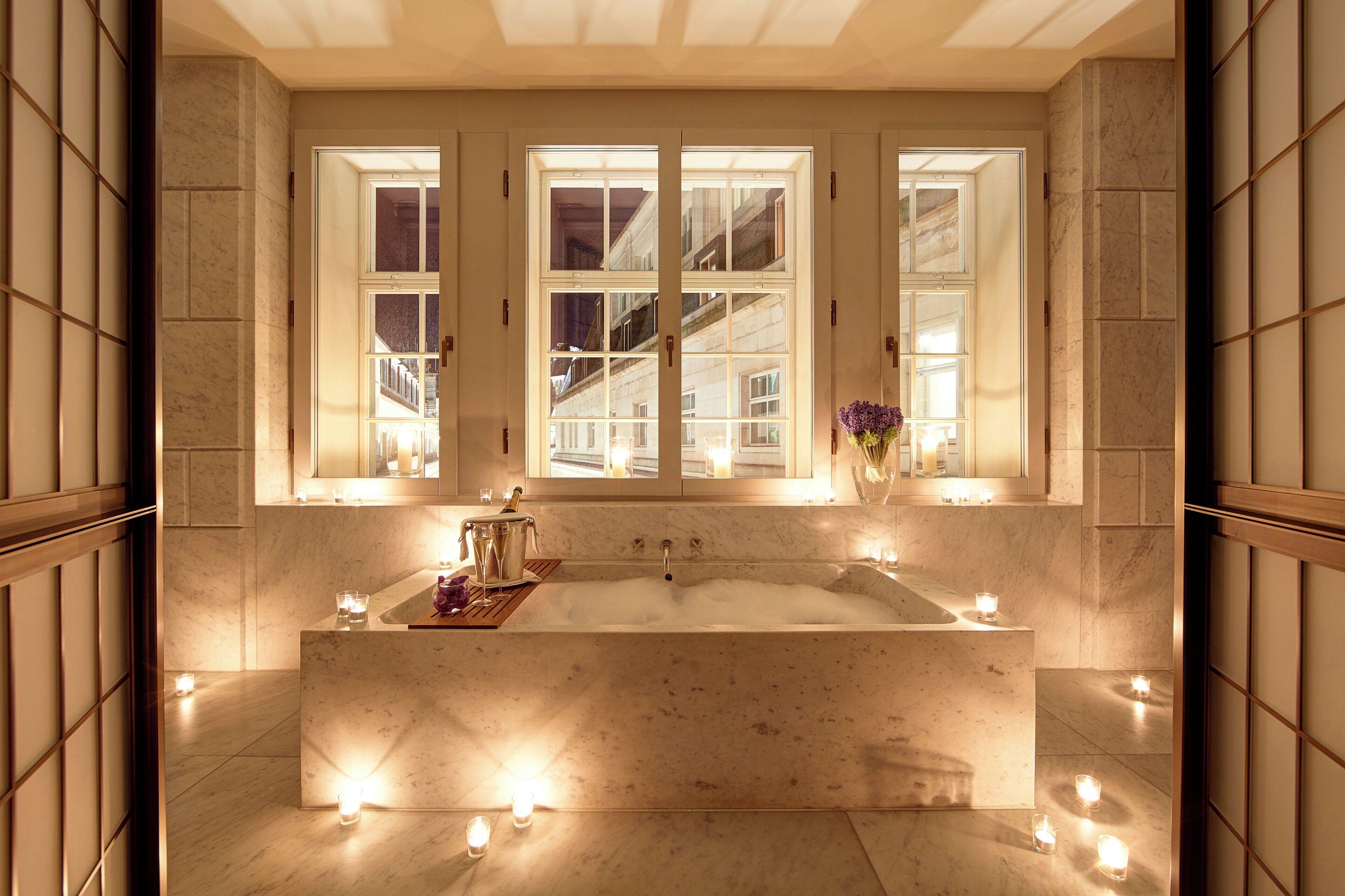A spacious bathroom with a large bathtub, multiple windows, and candles.