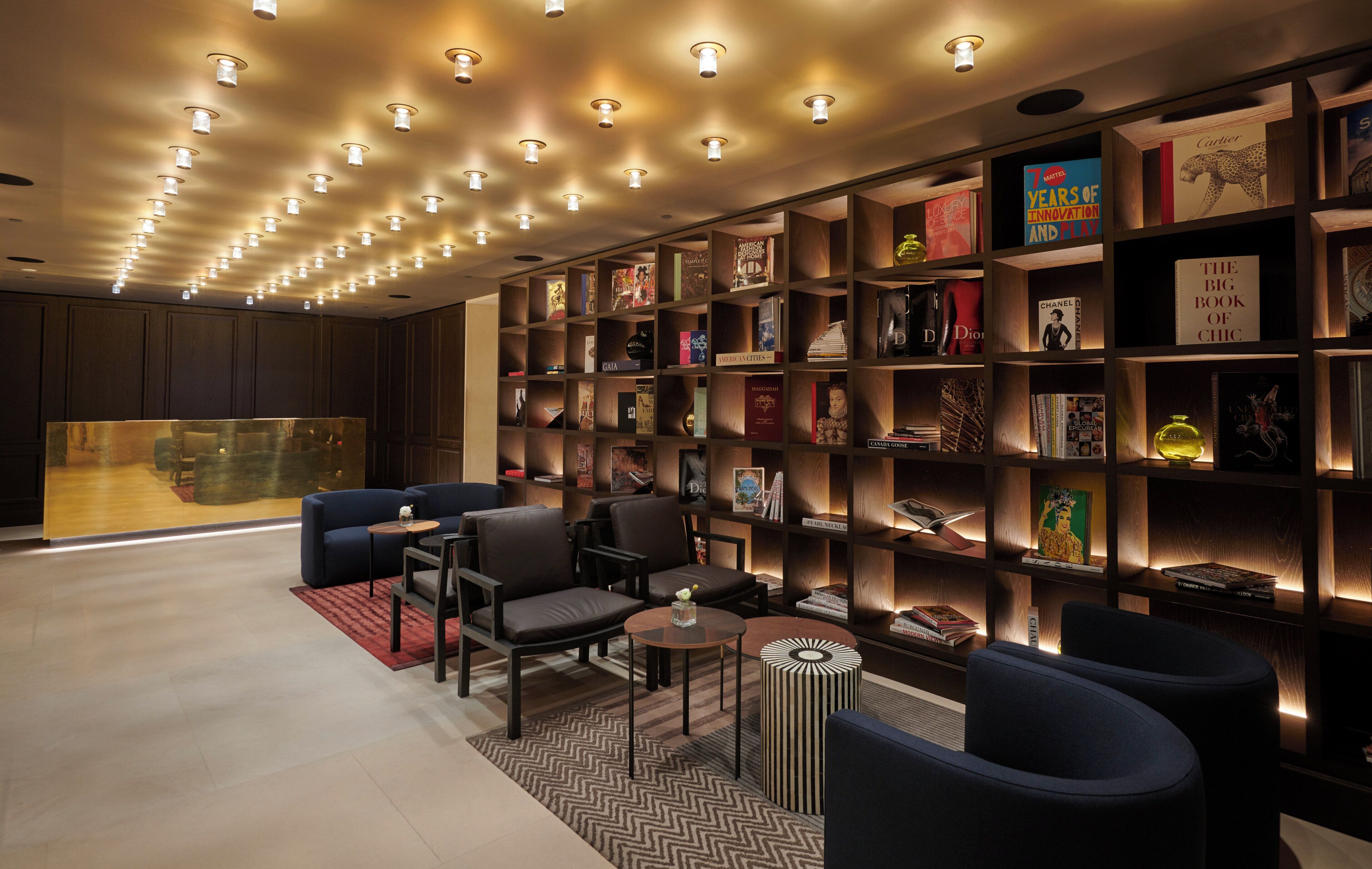 A modern library with bookshelves, comfortable seating, and a large window.