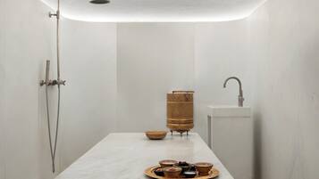 A modern bathroom with a shower, a sink, and a tray of toiletries.
