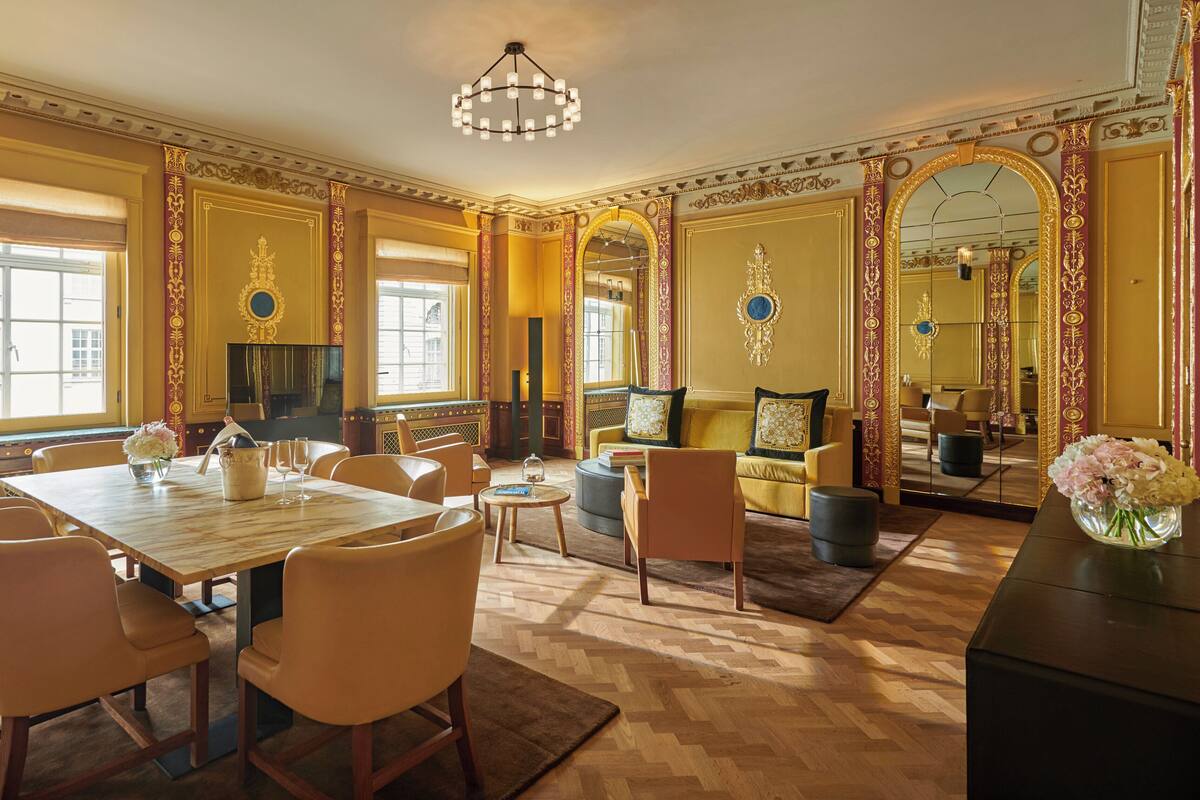 A luxurious room with a large dining table, comfortable seating, a television, and ornate decor.
