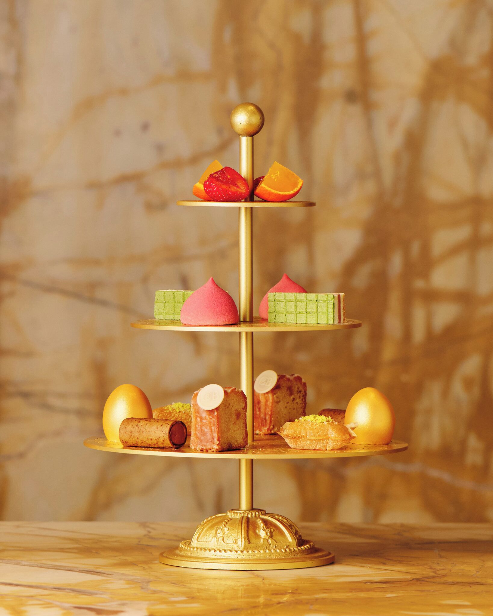 A three-tiered dessert stand with various pastries and fruits.