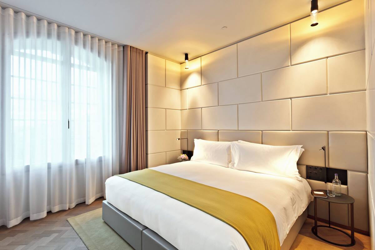 A modern hotel room with a large bed, a bedside table, and a nightstand.