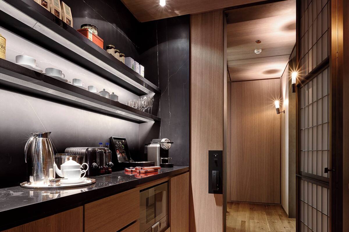 A modern kitchen with wooden cabinetry, a black countertop, and a wooden floor.