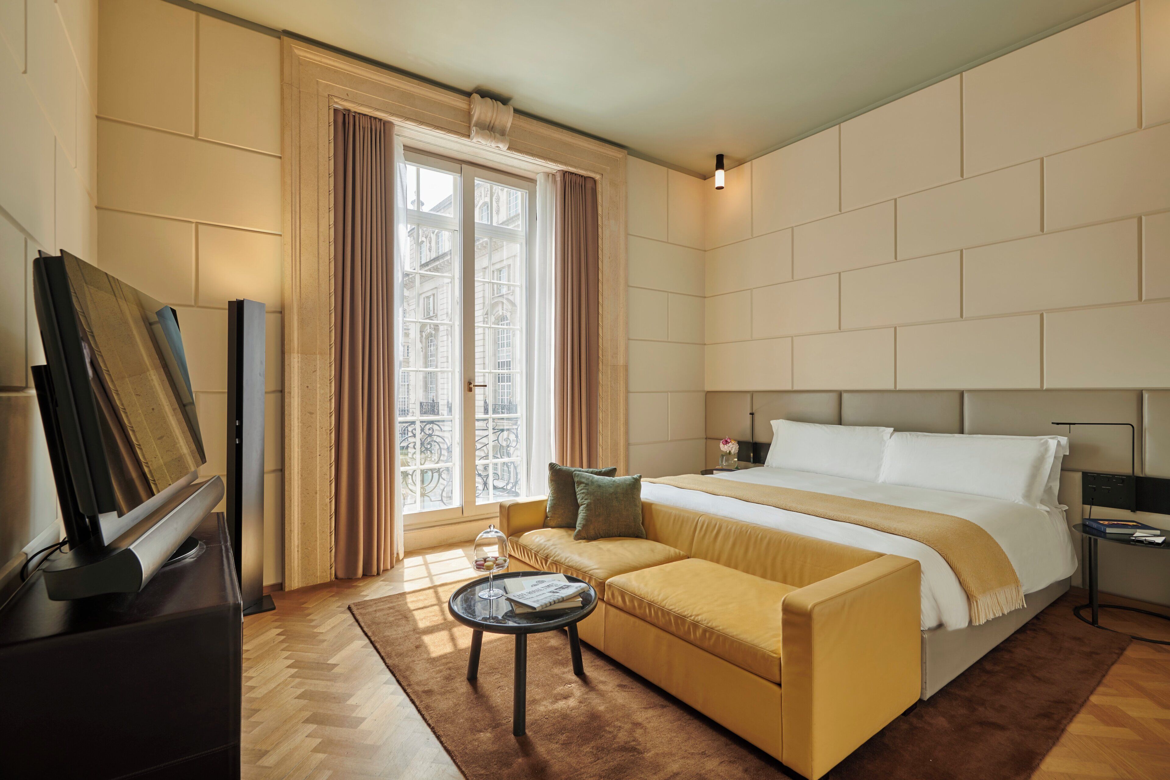 Ein Hotelzimmer mit einem großen Bett, einer Couch, einem kleinen Tisch und einem Fernseher.
