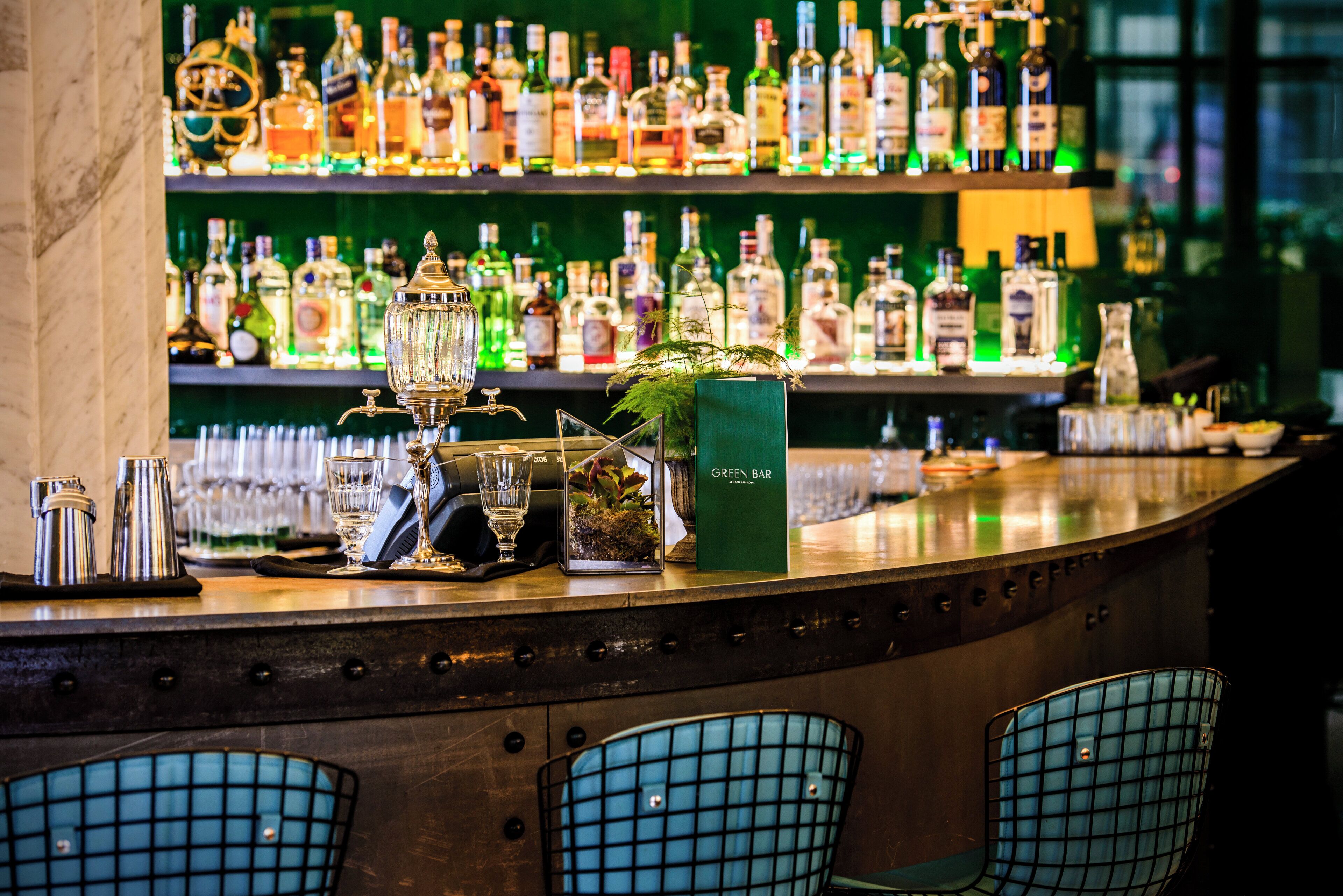 A bar with a variety of liquor bottles, glasses, and a green bar sign.