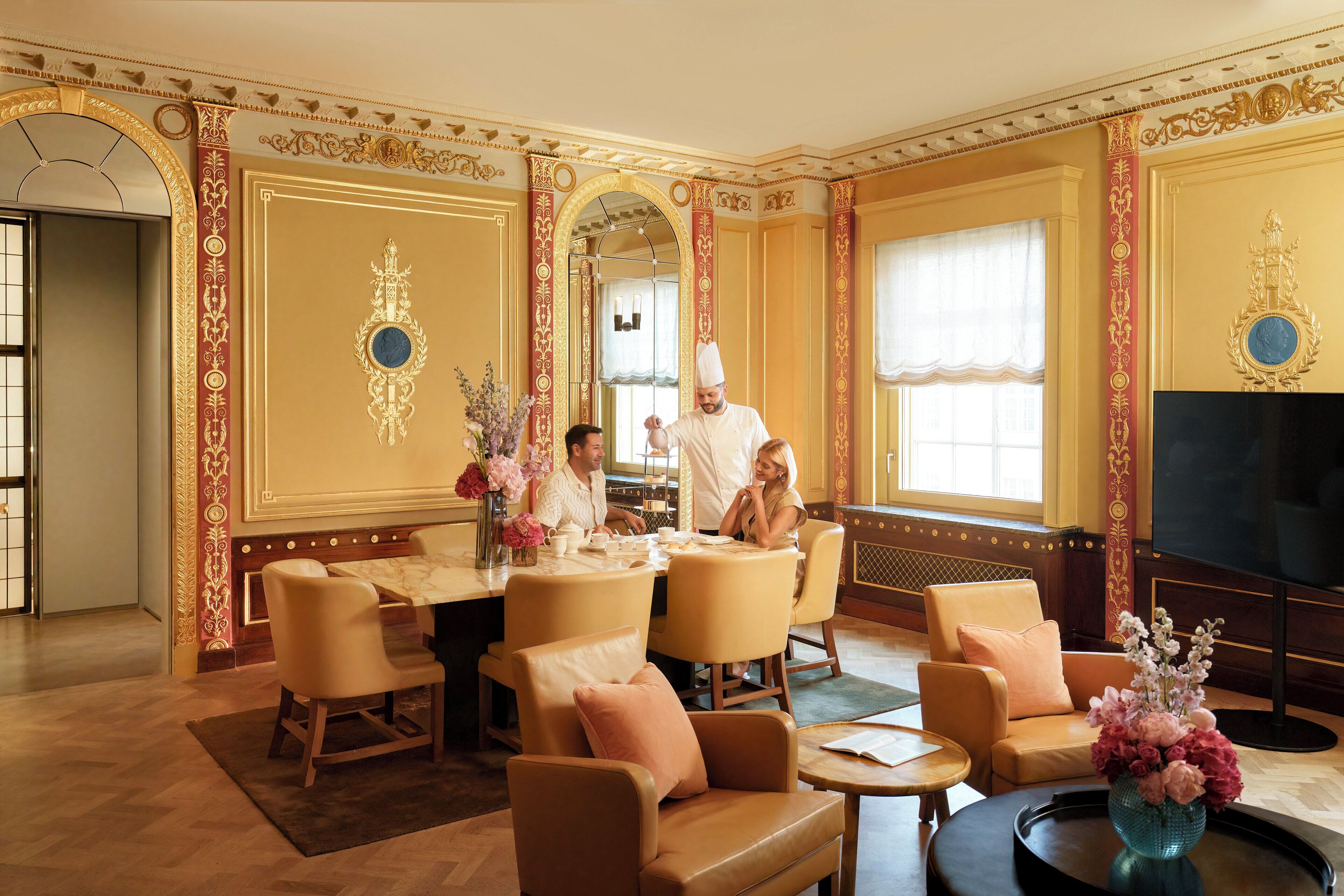 Een luxe hotelkamer met een eethoek, een televisie en een groot raam.