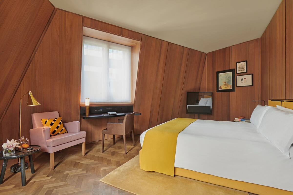 A bedroom with a bed, desk, chair, and a window.