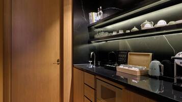 Una cocina moderna con cubierta de color negro, una puerta de madera y un estante con cristalería y teteras.
