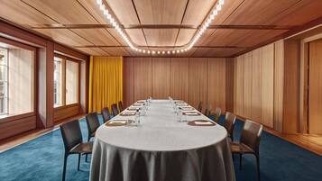 Una sala de conferencias con una larga mesa, sillas y una alfombra azul.