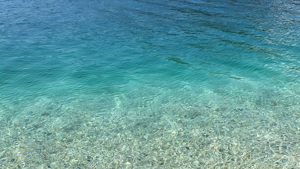 On voit clairement une plage de galets bordée par l’eau.
