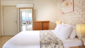 Une chambre d’hôtel avec un lit, une armoire en bois, une porte-fenêtre coulissante donnant sur un balcon et un mur en briques.