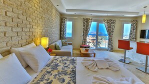 Une chambre d’hôtel avec un mur en briques, un lit recouvert d’une couvre-lit à motifs floraux, un canapé, une table basse, une télévision et un balcon avec vue.