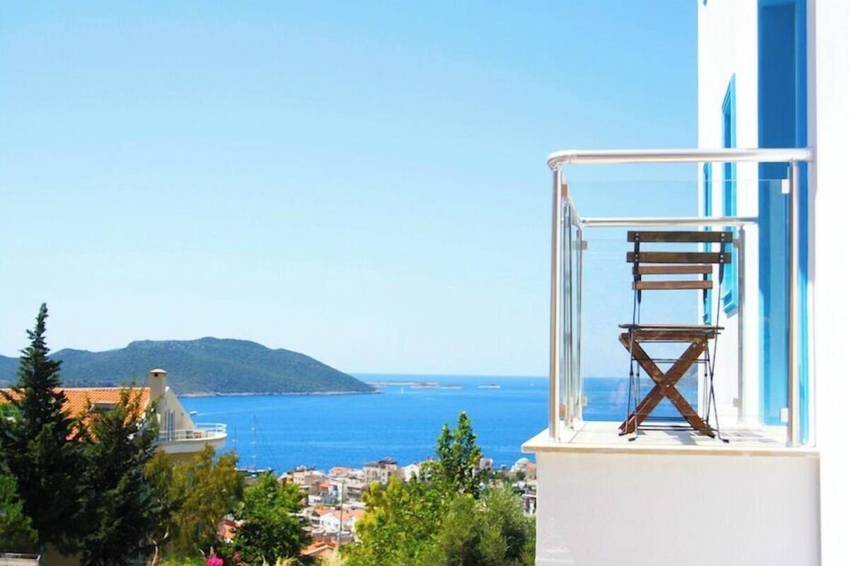 A balcony with a view of the sea and a distant mountain.