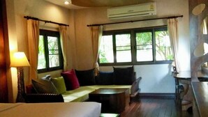 A hotel room with a bed, a sofa, a small table, and a window with curtains. - Bura Resort, Chiang Rai (Chiang Rai)