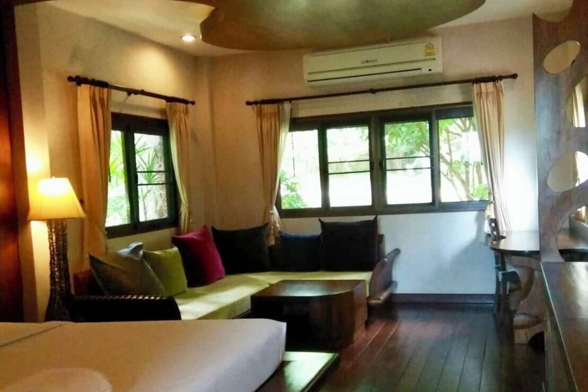 A hotel room with a bed, a sofa, a small table, and a window with curtains.