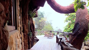 A wooden deck with a rustic stone wall and a wooden railing.