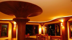A dining area with a central round table surrounded by chairs, wooden columns, and warm ambient lighting. - Bura Resort, Chiang Rai (Chiang Rai)