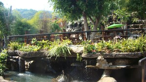 A wooden deck with a small waterfall and lush greenery. - Bura Resort, Chiang Rai (Chiang Rai)