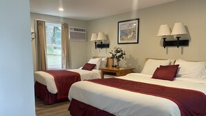 A hotel room with two beds, beige walls, a window with curtains, a painting, and two wall-mounted lamps. - Cutty Sark Motor Lodge (Dennis Port)