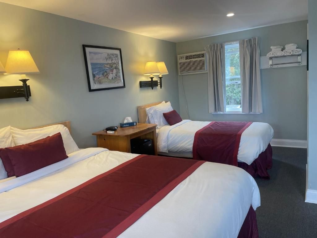 Une chambre d’hôtel avec deux lits, une table de chevet, une lampe, un tableau, une fenêtre avec des rideaux et un porte-serviettes.