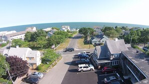 A residential street with houses, parked cars, and a clear view of the ocean. - Cutty Sark Motor Lodge (Dennis Port)