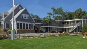 A two-story house with a large porch and a flagpole. - Cutty Sark Motor Lodge (Dennis Port)