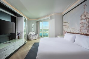 Une chambre d’hôtel avec un grand lit, une télévision, un canapé et un balcon avec vue.