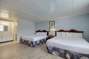 Una habitación de hotel con dos camas, un tocador con espejo e iluminación empotrada en el techo.