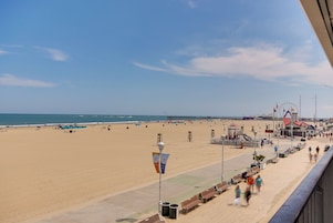 Uma praia com calçadão, roda gigante e torre de salva-vidas.