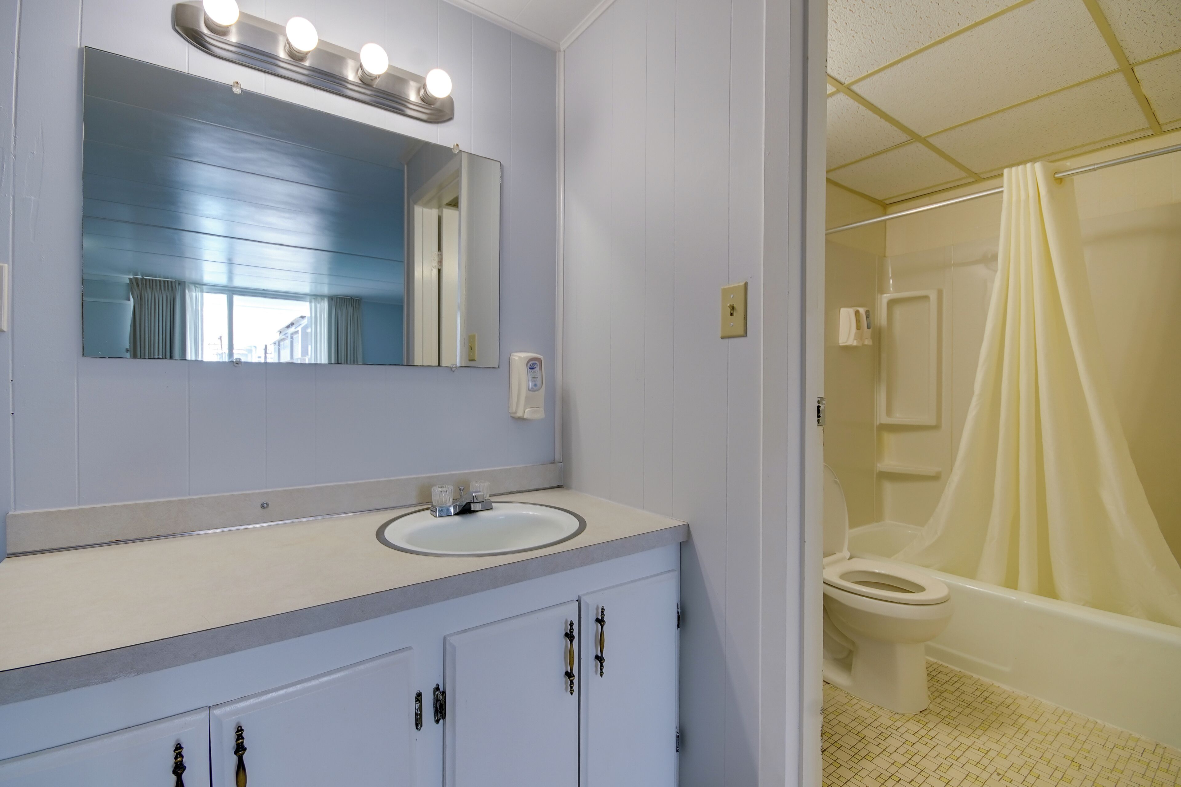 Un baño con lavabo, espejo e inodoro.