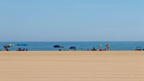 A beach with people and umbrellas.