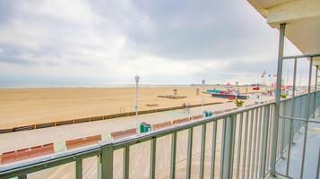 Vista da praia a partir de uma varanda com deck de madeira, uma torre salva-vidas e comodidades de praia.