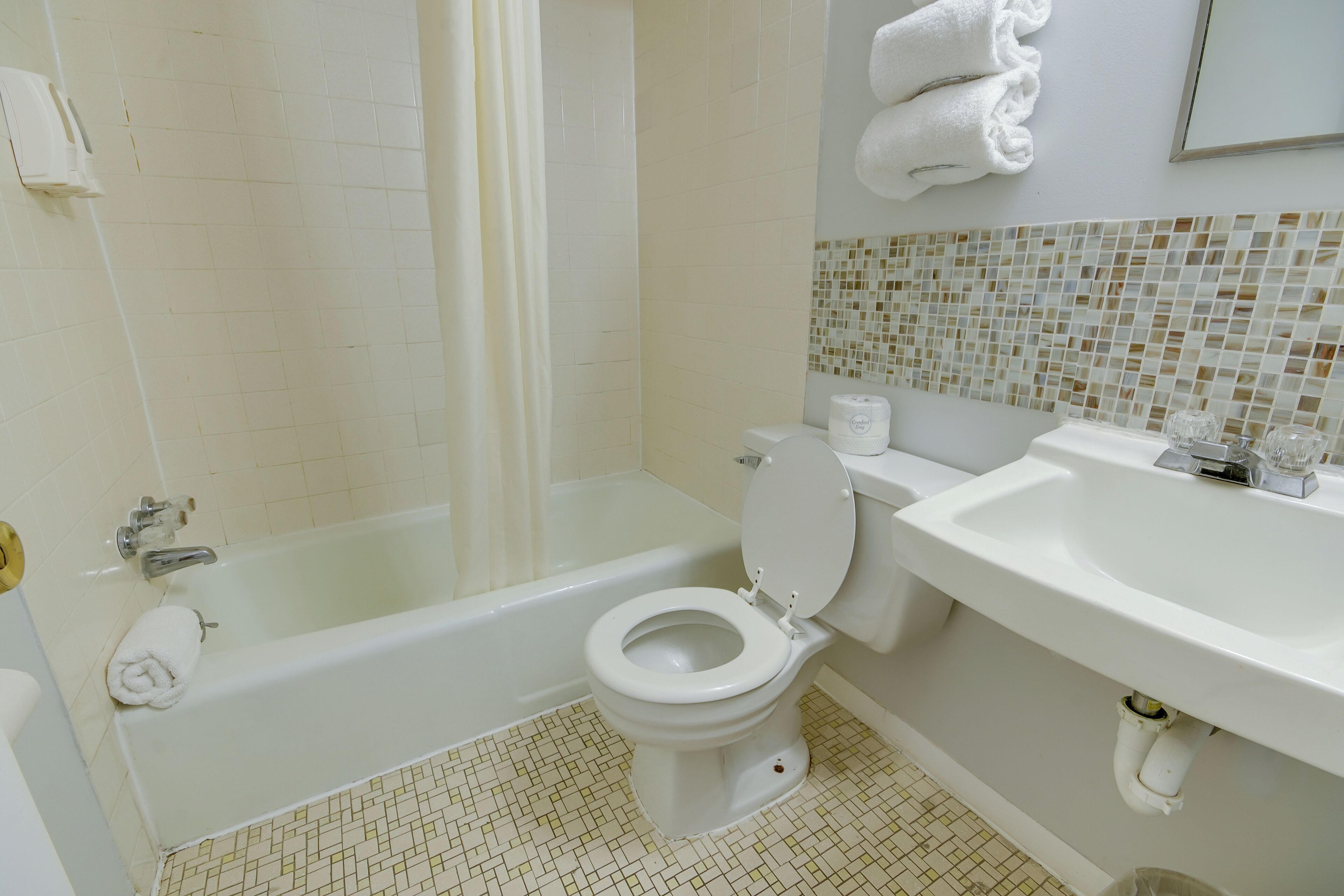 A bathroom with a bathtub, toilet, sink, and a shower curtain.