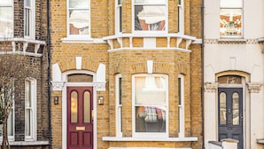 A two-story brick townhouse with a red front door, white-framed windows, and a "No Parking" sign. - Clapham Guest House (London)