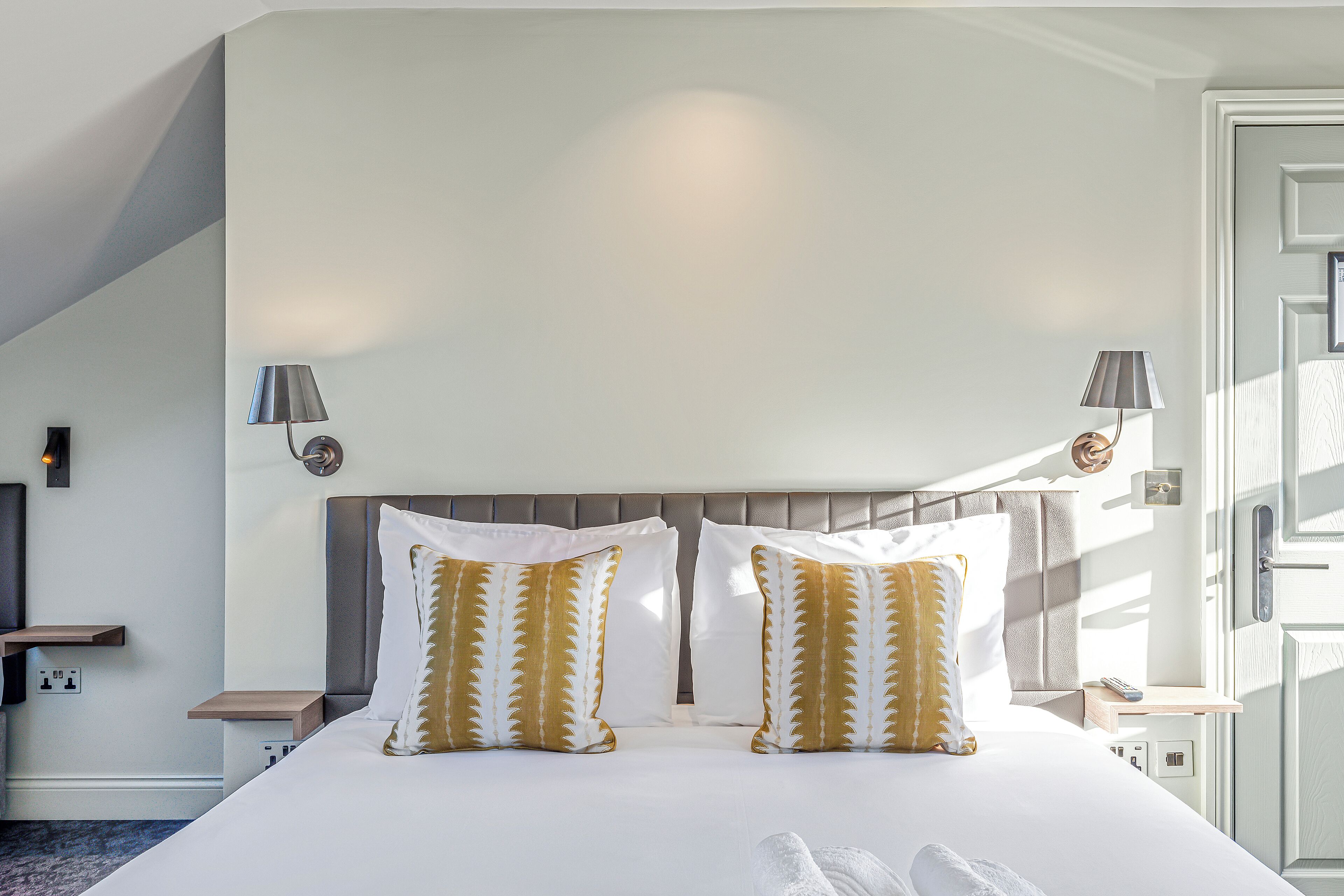 Quarto de hotel com uma cama grande, duas luminárias de cabeceira, mesa de cabeceira e vista para o exterior.