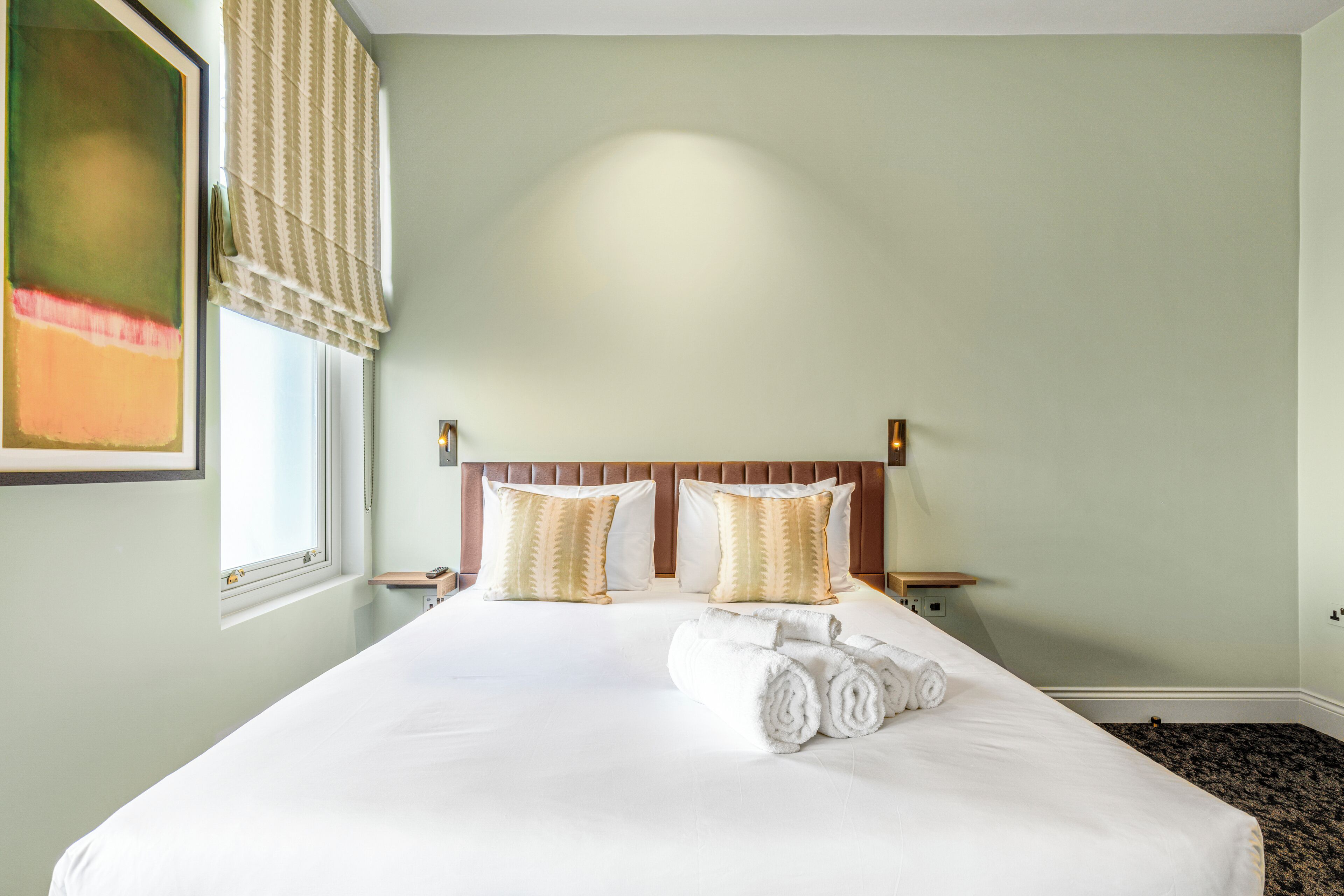 Hotelkamer met een groot bed, twee nachtkastjes, een hoofdeinde en een raam met uitzicht.