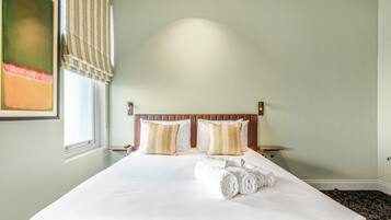 Hotelkamer met een groot bed, twee nachtkastjes, een hoofdeinde en een raam met uitzicht.