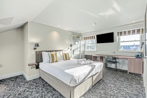 A modern hotel room with a large bed, a desk, and a view of the city. - Clapham Guest House (London)