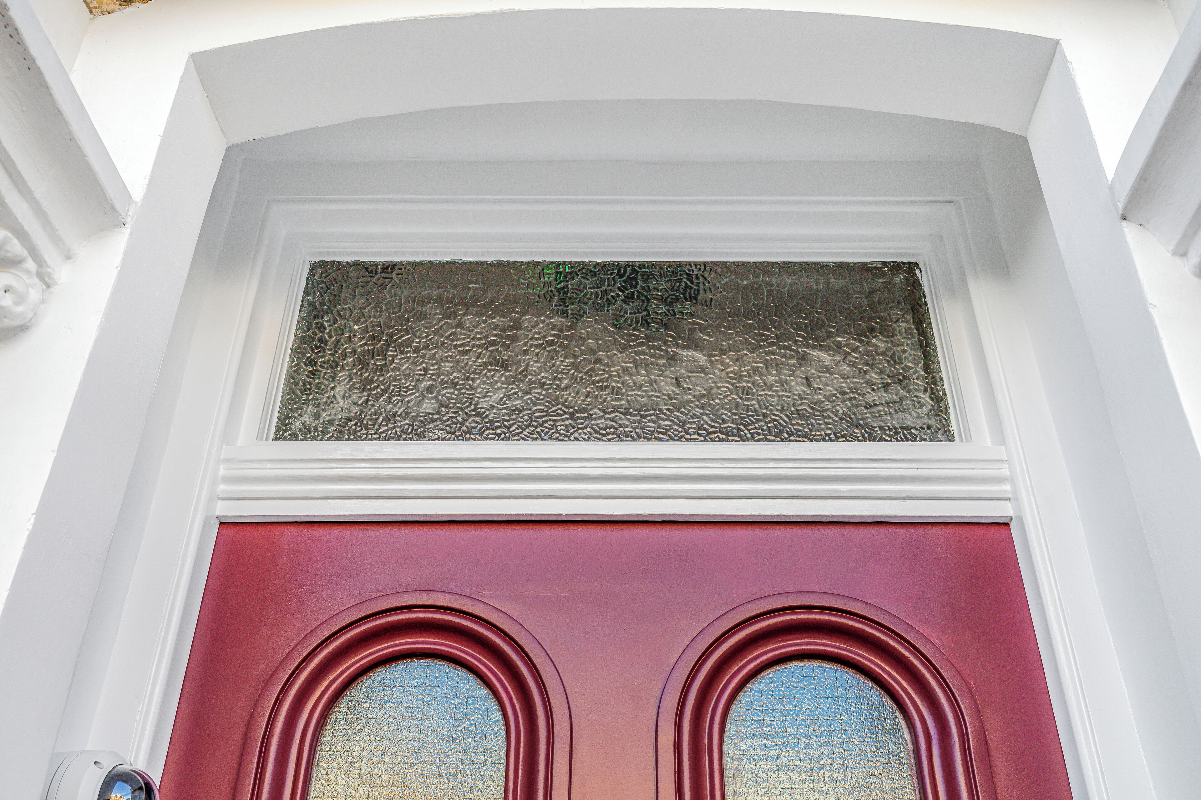 A red door with a textured glass window above it.