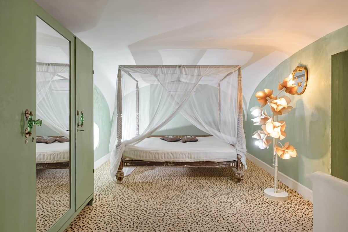 Une chambre à coucher avec un lit à baldaquin, un miroir et une lampe sur pied.