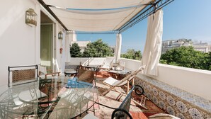 Un balcon avec une table en verre, des chaises et une vue sur la ville.