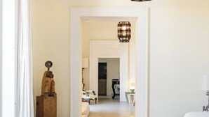Un salon spacieux avec un grand pouf, une lanterne suspendue et une vue sur la salle à manger.