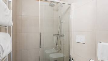 Un baño moderno con ducha envuelta en vidrio, inodoro y bidé.