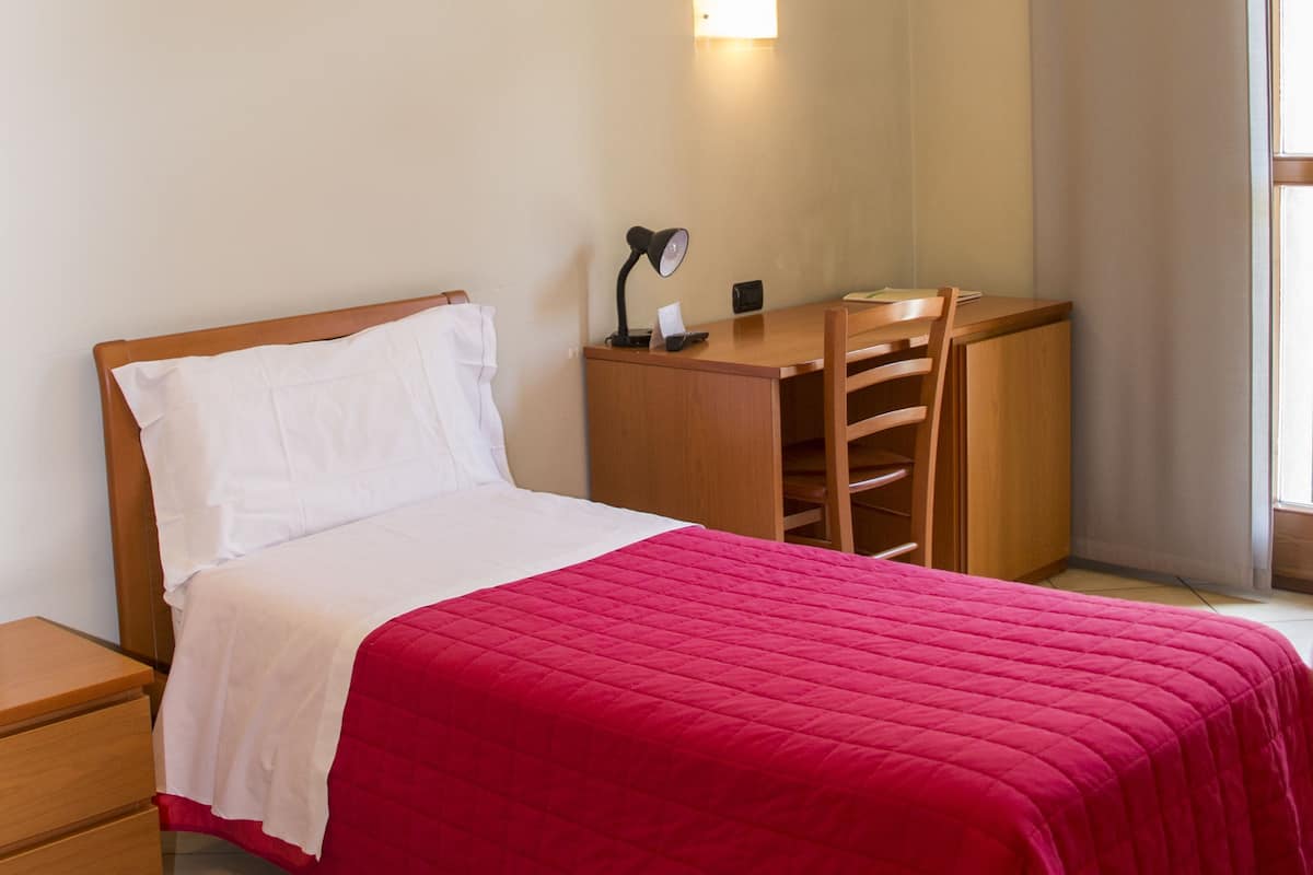 A neatly arranged bedroom with a bed, a desk, and a chair.