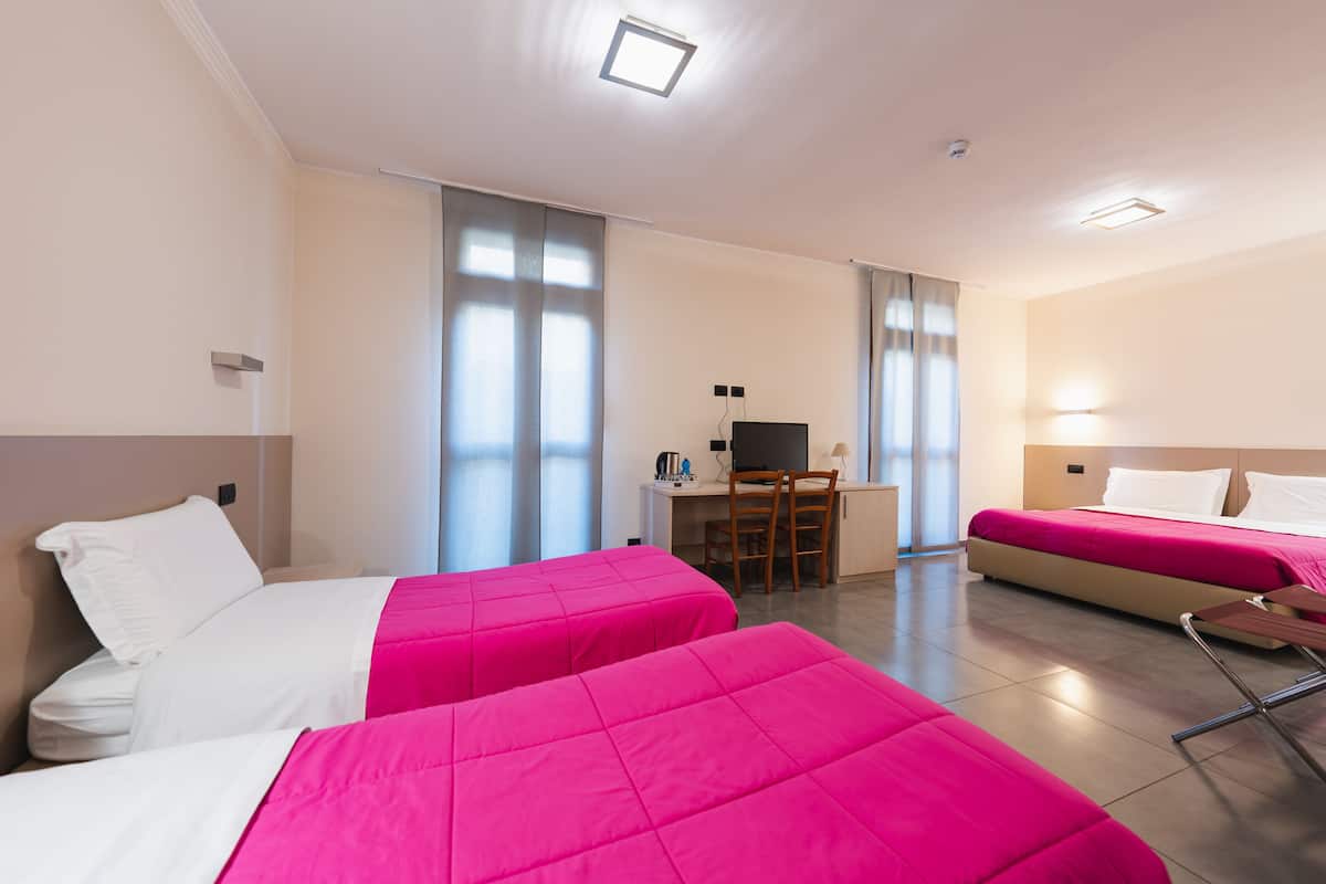 A hotel room with two beds, a desk, and a chair.